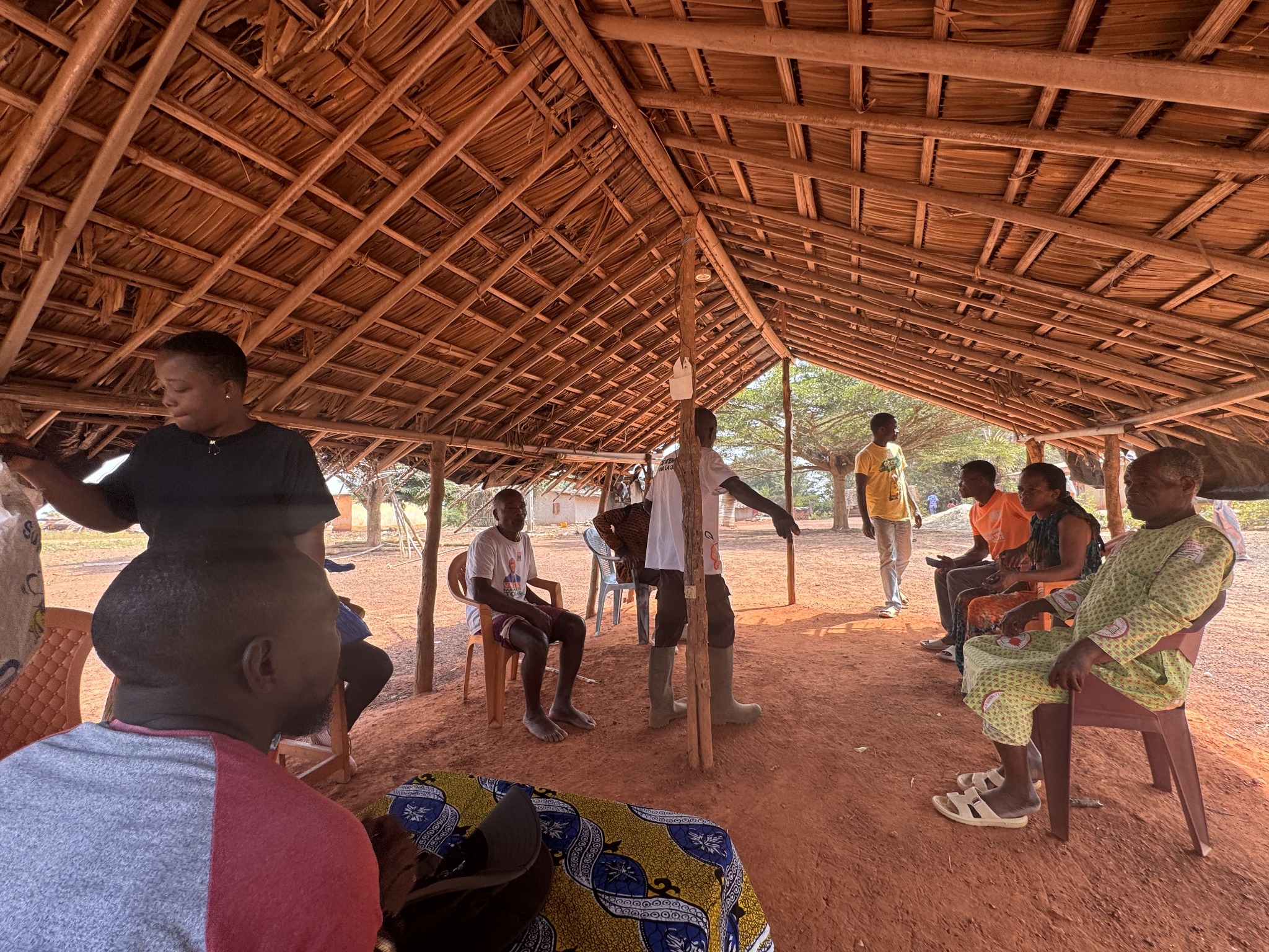 Community members meeting under a thatched shelter in Côte d’Ivoire